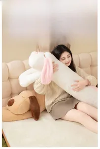 Extra long plush dog pillow in sprawled position shown with model on sofa