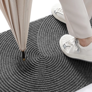 Close-up of dark grey anti-slip doormat with spiral texture and a wet umbrella