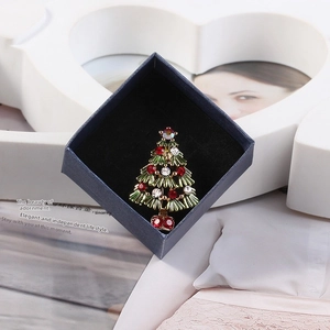 Detailed shot of a crystal-encrusted Christmas tree brooch in a premium gift box