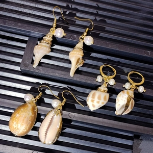 Golden shell earrings with natural mother-of-pearl and white pearls on a grey background