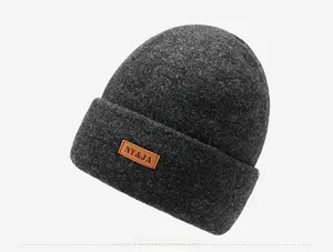 Detailed side view of dark grey knitted beanie featuring a brown leather logo patch
