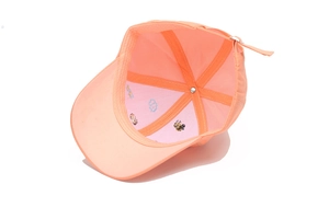 Close-up of internal cartoon bee embroidery and metal adjustment buckle on orange cap
