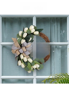 Detail of tulip wreath with wooden Welcome sign and bow against a white window frame