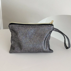 Detail der silbernen Glitzer-Kosmetiktasche mit goldenem Reißverschluss und Trageschlaufe