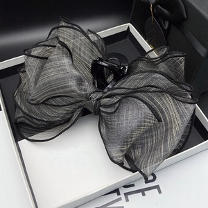Grey mesh bow hair claw clip with black piping displayed in a luxury gift box