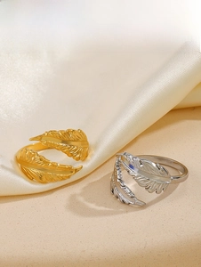 Detail of feather-shaped open rings in gold and silver finish on silk fabric