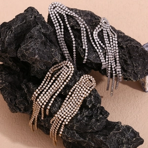 Detail of silver and gold tassel earrings with micro-set rhinestones on a black stone