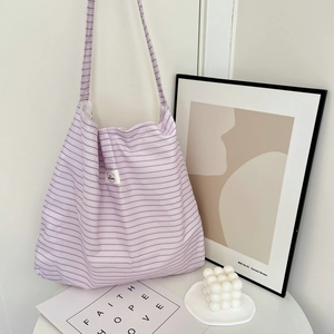 Detail of light purple striped canvas tote bag with minimalist white logo tag