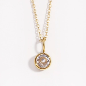 Macro detail of gold necklace featuring round bezel-set clear crystal on O-chain
