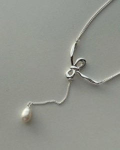 Detail view of silver bow pendant with natural freshwater pearl on a delicate chain