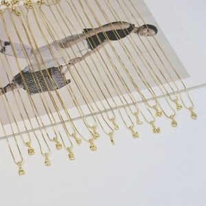 Detail view of 18k gold plated bubble letter necklaces from A to Q on white background