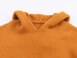 Gros plan détaillé du col en V et de la texture de la capuche de ce pull en maille moutarde