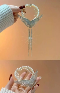 Detail of luxury gold hair claw with pearl inlay, rhinestone wings, and long fringe tassels