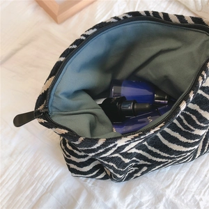 Macro detail of zebra print makeup bag interior showing green canvas lining and zipper
