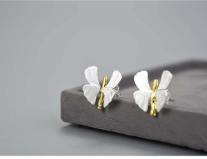 Macro shot of silver and gold butterfly earring showing brushed metal textures