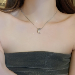 Close-up of minimalist silver crescent moon pendant necklace on snake bone chain