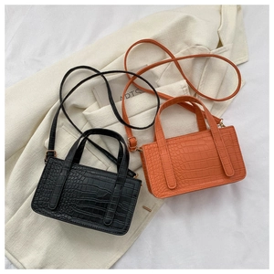 Close-up of black and orange crocodile pattern square handbags with luxury texture