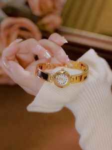 Detail of elegant gold watch with amber tortoiseshell strap and white Roman numeral dial