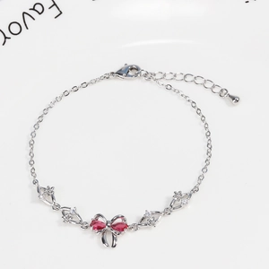 Detail of silver bow bracelet with red heart zircons and lobster clasp closure