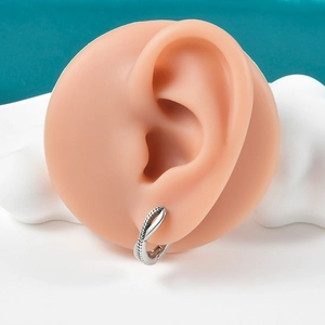 Detail of twisted silver ear cuff featuring polished and beaded texture on model