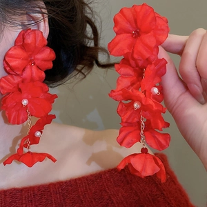 Detail view of bridal red fabric flower earrings with pearls and long gold chain