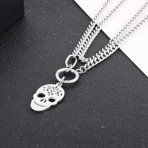 Close-up of a silver skull pendant with hollow carving on a thick stainless steel chain