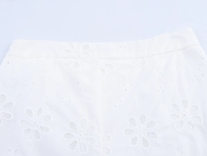 Nahaufnahme der floralen Lochstickerei auf weißen Baumwollshorts im französischen Stil