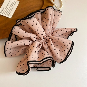 Detail of nude pink polka dot chiffon scrunchie with black lace trim on a wooden tray