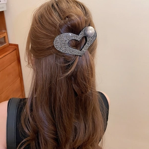 Detail showing crystal heart hair claw with grey pearl on brown wavy hair