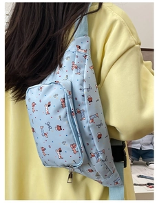 Detail of light blue crossbody bag with cartoon dog prints and adjustable strap worn on hoodie