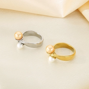 Detailed macro of gold and silver crossover rings with dual pearls on silk fabric