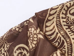 Detailopname van bruine chiffon stof met beige print en nauwkeurige randafwerking