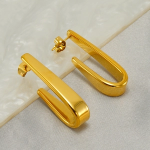 Minimalist gold U-shaped stainless steel earrings on a white marble background