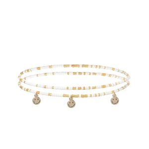 Détail de la chaîne de taille en perles blanches et dorées avec trois breloques smiley