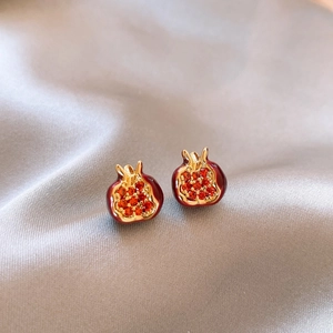 Macro shot of red pomegranate stud earrings with gold plating on grey silk background