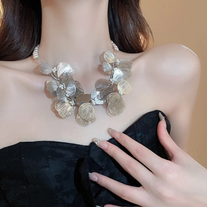 Macro detail of silver metal hollow flower necklace with brushed texture and pearls