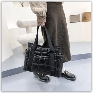Model holding black quilted puffer tote bag with glossy waterproof nylon finish