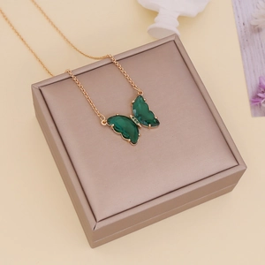Detail of a green glass butterfly pendant on a gold chain displayed on a jewelry box
