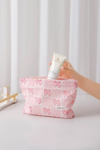 Dettaglio della borsa trucco a scacchi rosa e bianchi con fiocco rosso e zip in metallo