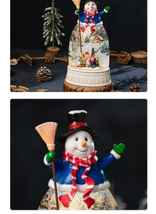 Detailed view of snowman snow globe with swirling glitter and festive resin base
