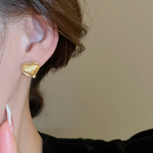 Close-up of a model wearing the brushed gold heart-shaped stud earring for a modern look