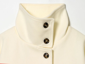 Detail of cream wool coat collar with stand-up neck and brown tortoiseshell buttons