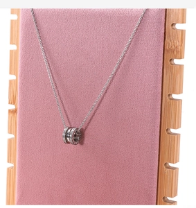 Macro shot of silver-plated triple-ring necklace with zircons on pink velvet display