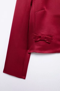Detailed close-up of dark red long sleeve top featuring an elegant waist bow decoration