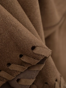 Gros plan de la veste en daim marron montrant les coutures tressées et la texture mate