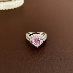 Macro shot of silver ring featuring heart-shaped pink zircon and halo diamond setting