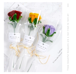 Detailed close-up of handmade crochet roses in red, yellow, and purple with clear packaging