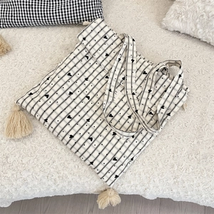 Close-up of black and white checkered canvas tote bag with heart prints and tassels
