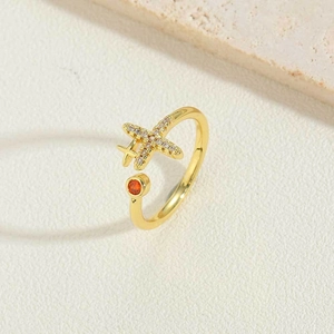 Macro shot of gold airplane ring with white zircon stones and a red gemstone accent
