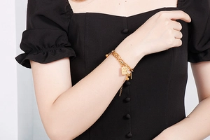 Detail of double-layer gold chain bracelet with rectangle poker pendant and steel beads